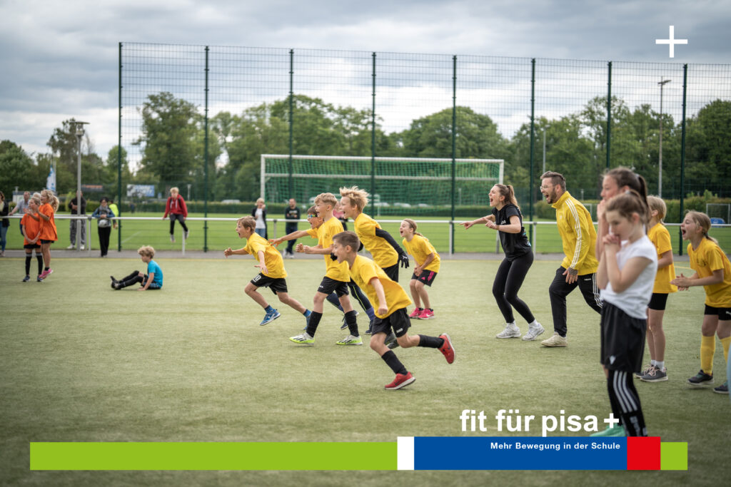 Kinder in gelben Hemden und zwei Erwachsene laufen auf einem Sportplatz. Im Hintergrund ein Fußballtor und Zuschauer. Der Text lautet „fit für pisa+ Mehr Bewegung und gesunde Ernährung in der Schule.“.